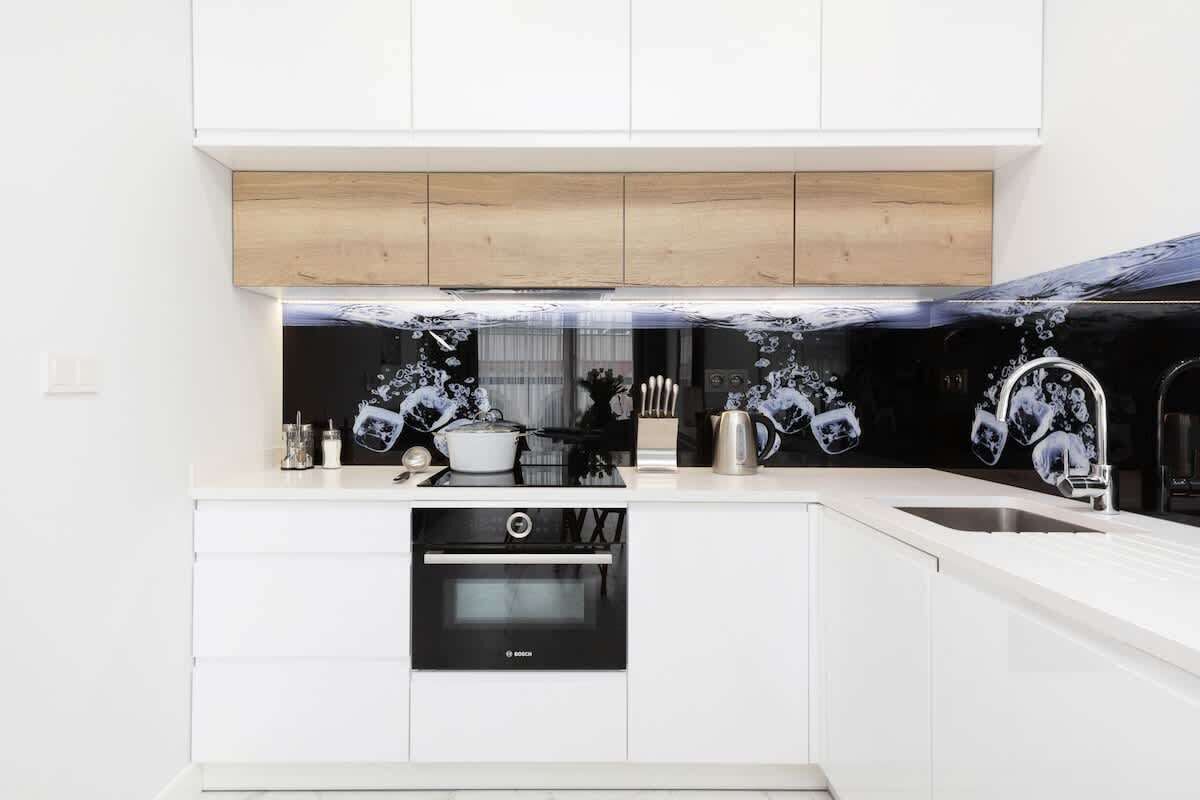 A modern kitchen with white cabinetry, a Bosch oven, and a black backsplash with floral patterns.