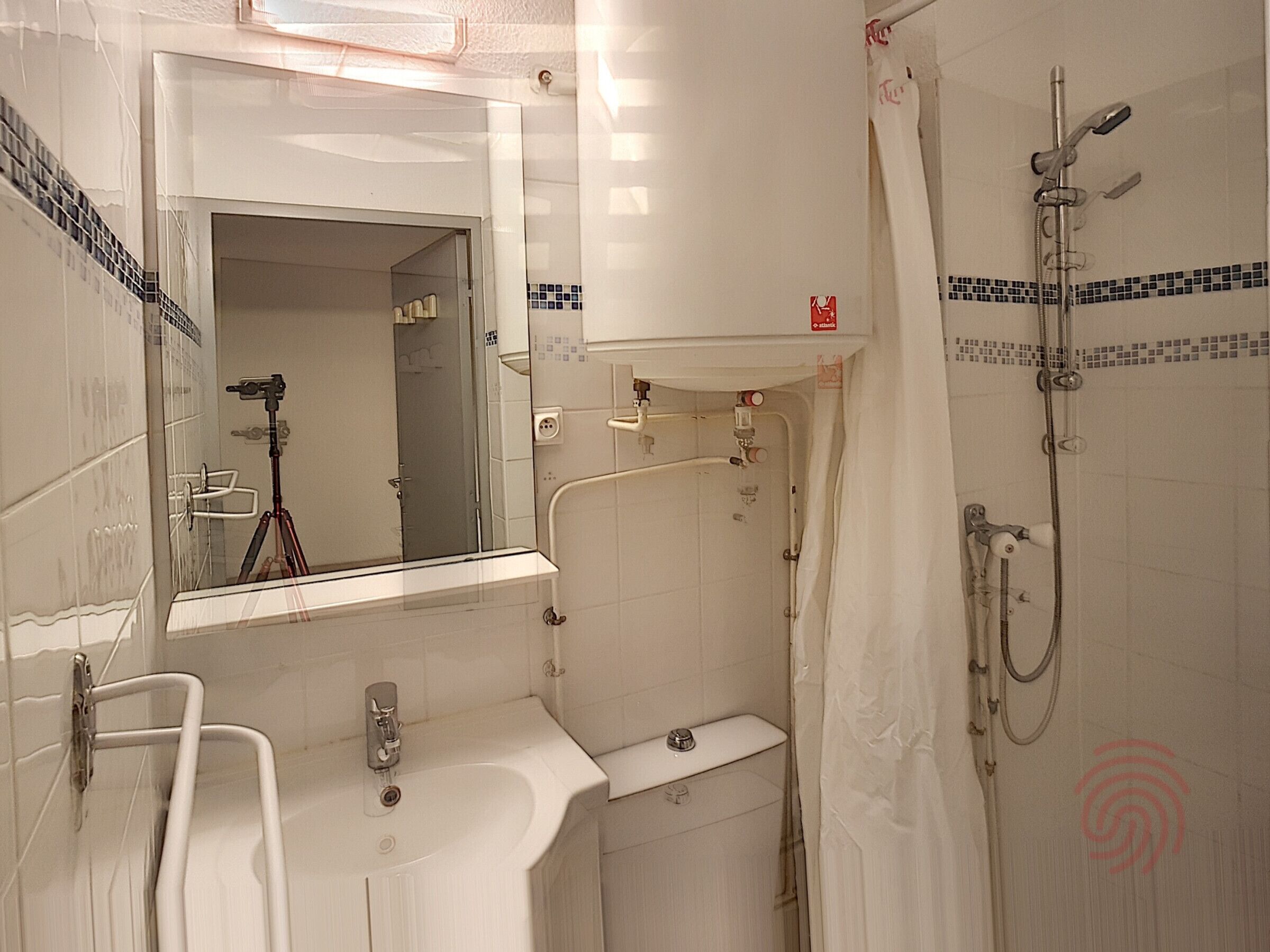 A bathroom with a sink, mirror, shower, and tiled walls.