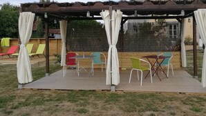 A covered outdoor seating area with a wooden deck, a table, and chairs.