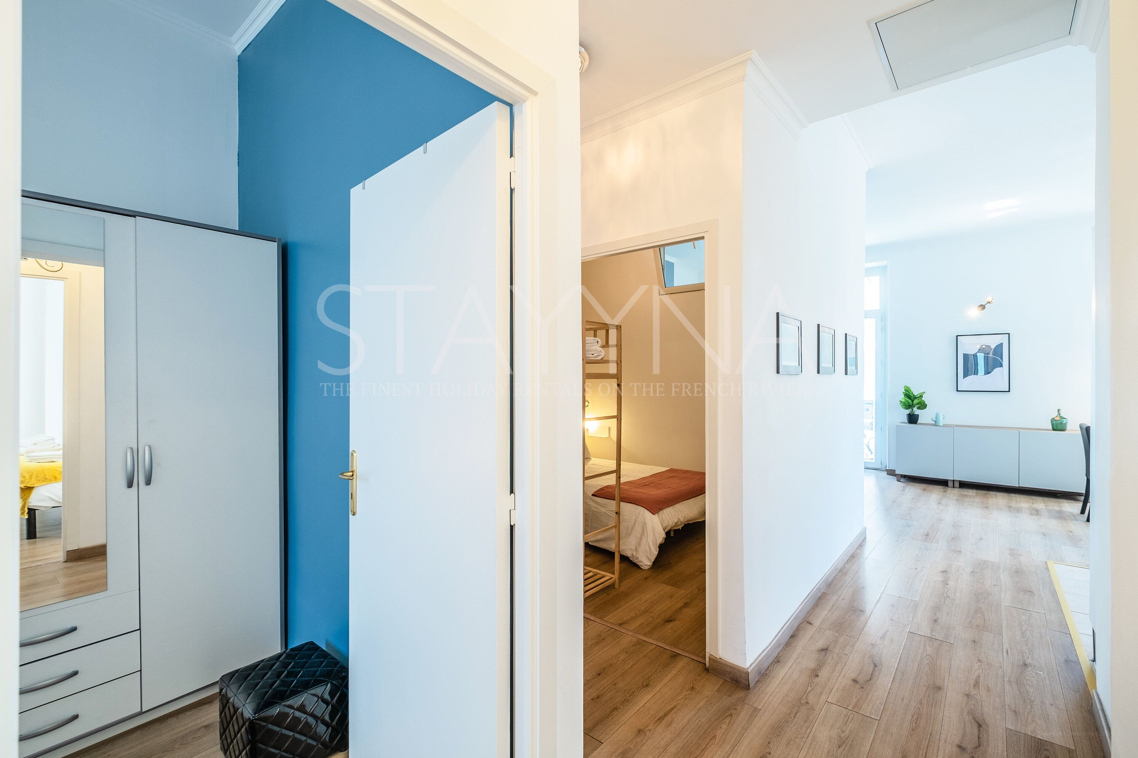 A modern interior with a blue accent wall, a wardrobe, and a bed in a separate room.