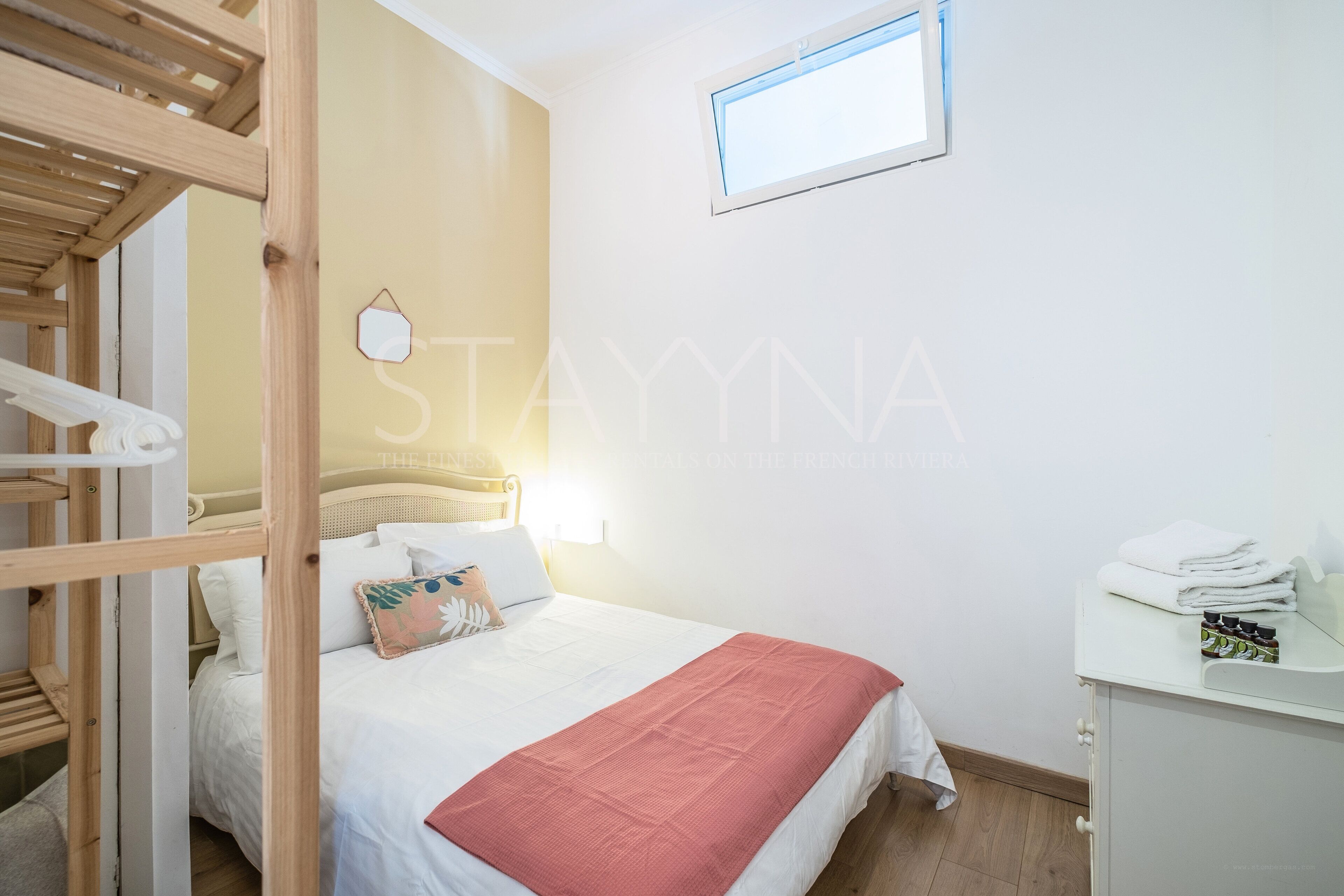 Une chambre à coucher avec un lit, un escalier en bois, une fenêtre et une petite table de chevet avec des serviettes.
