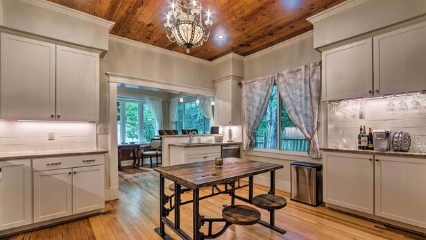 A spacious kitchen with wooden floors, white cabinetry, and a central island. - Spacious & Updated 1920's HSNP Craftsmen Home (Hot Springs)