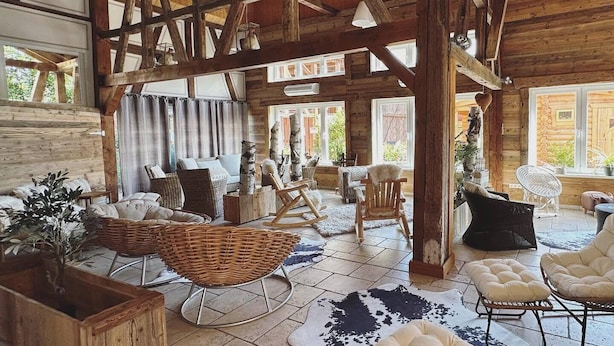 Un interior espacioso y rústico con vigas de madera a la vista, muebles de mimbre y diferentes opciones de asientos.