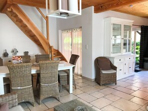 Ein Essbereich mit Korbstühlen, einem weißen Tisch und einer Treppe.