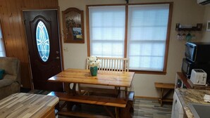 A kitchen with a wooden table, bench, and a refrigerator.