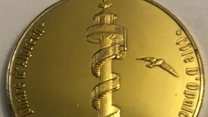 Moneda de oro con diseño en espiral y texto.