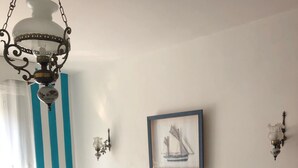 Un dormitorio con cama, una silla, un cuadro en la pared y una lámpara colgante.