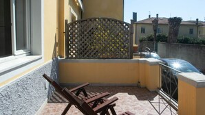 A balcony with a lattice partition, a car parked outside, and a building in the background. - N050 - Numana, three-room apartment in the center with porch and parking space (Numana)