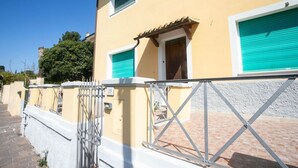 A yellow building with a gated entrance, a door, and a window with a green shutter. - N050 - Numana, three-room apartment in the center with porch and parking space (Numana)