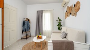 A modern living room with a white sofa, a round coffee table, and a wicker basket on a small table. - Erato Inn (Naxos)