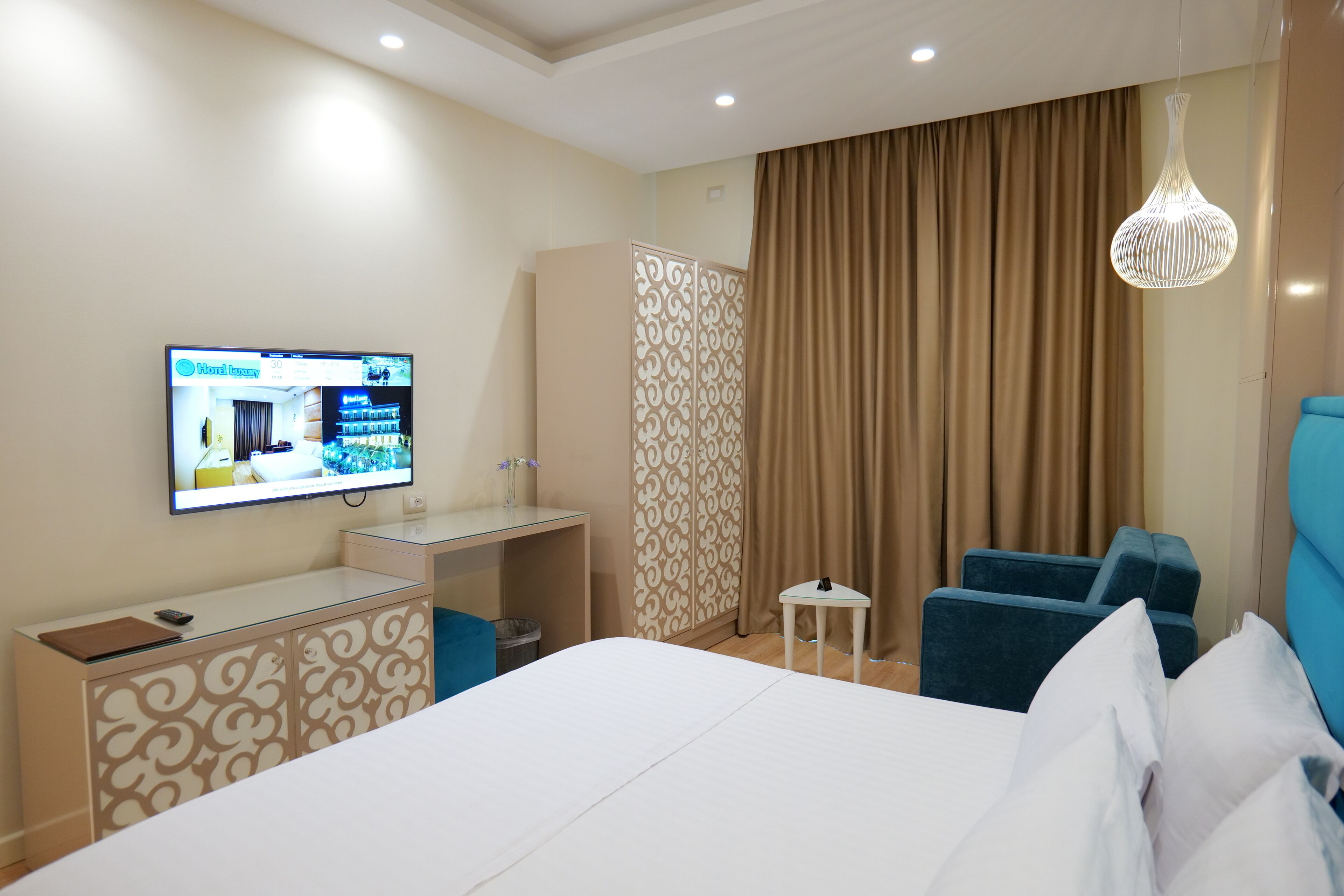 A hotel room with a bed, a desk, a chair, a television, and a curtain.