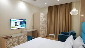 A hotel room with a bed, a desk, a chair, a television, and a curtain.