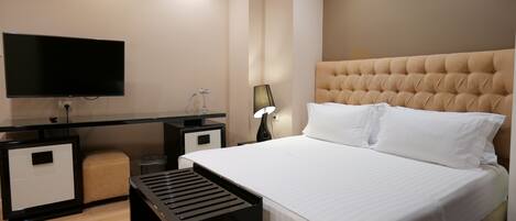 Una habitación de hotel con cama, televisión, escritorio y lámpara.