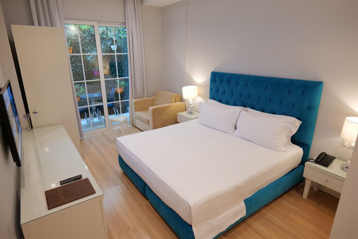 A hotel room with a large bed, a desk, a chair, and a view of the outdoors.
