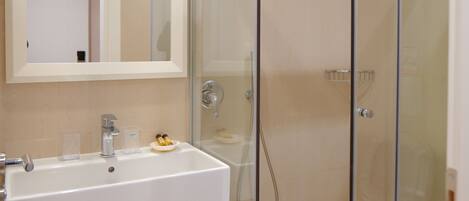 A modern bathroom with a glass-enclosed shower, a white sink, and a mirror above it.