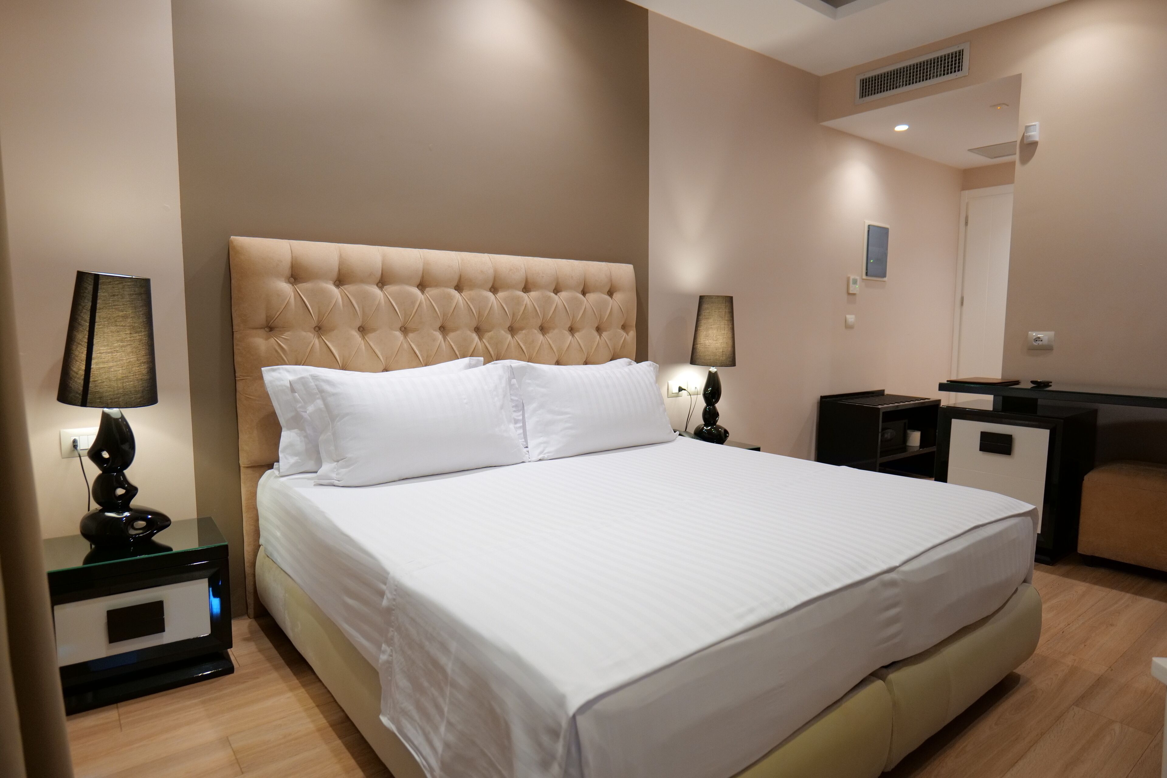 A neatly arranged hotel room with a large bed, two bedside tables with lamps, a small desk, and a chair.