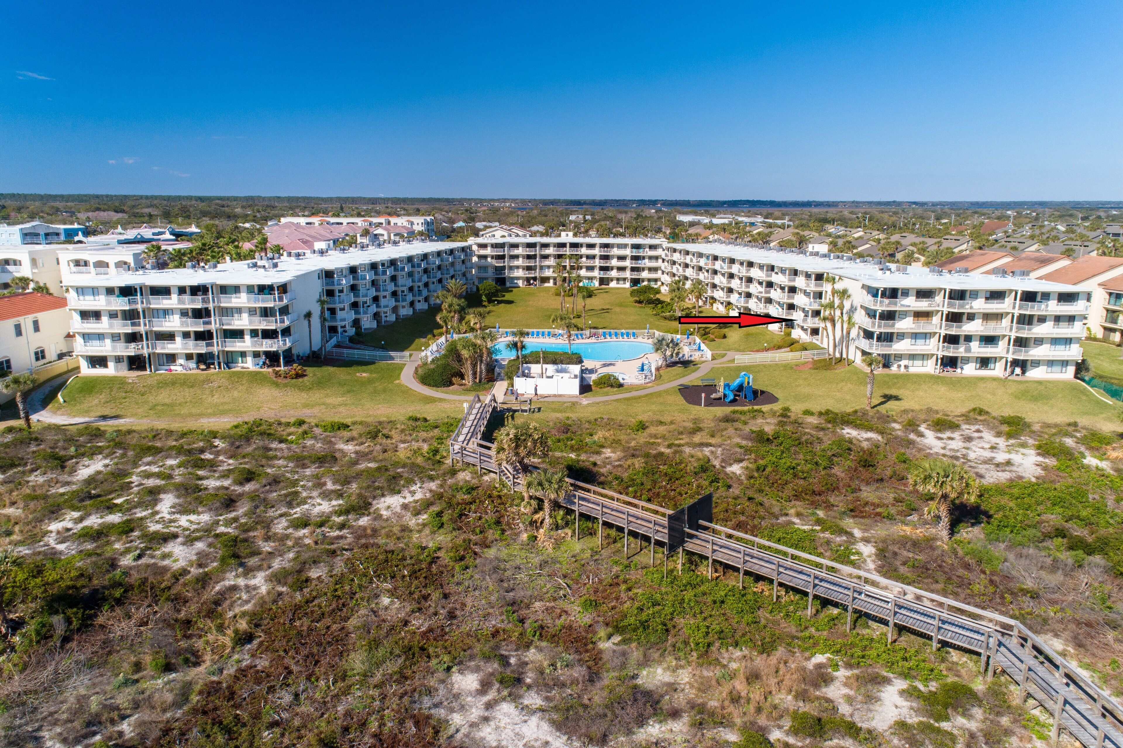 A large resort with multiple balconies, a central pool, and a boardwalk leading to the pool area.