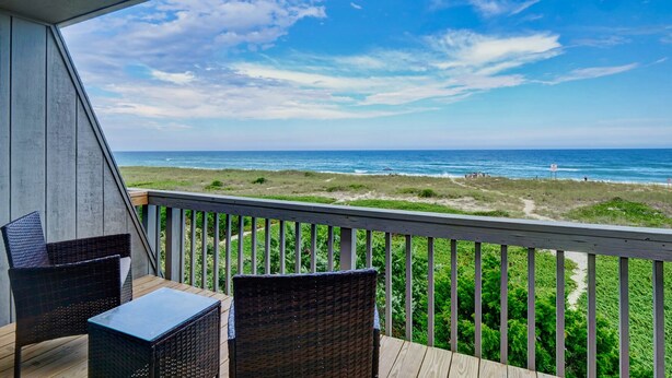 A balcony with wicker furniture overlooking a beach. - Oceanfront Townhome with Amazing Ocean Views (Wrightsville Beach)