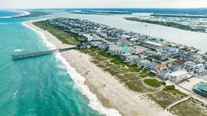 An aerial view of a coastal town with a pier extending into the ocean, beachfront properties, and a marina. - Oceanfront Townhome with Amazing Ocean Views (Wrightsville Beach)