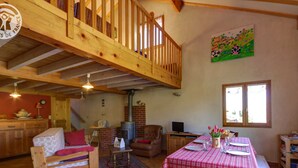 A rustic cabin interior with a loft bedroom, a dining area, and a kitchen.