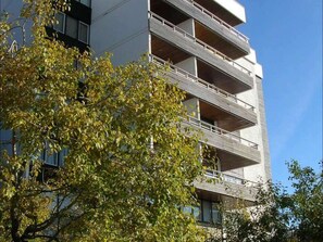 A multi-story building with balconies, surrounded by trees.