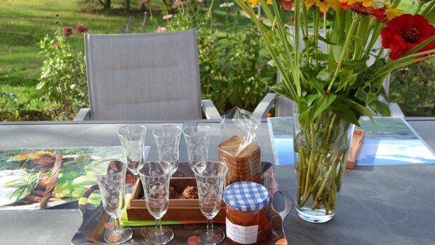 A table set outdoors with a glass tray holding wine glasses, a loaf of bread, and a jar of jam. - Cozy rental with garden, fireplace, and pet-friendly near Roanne (La Tuilière)