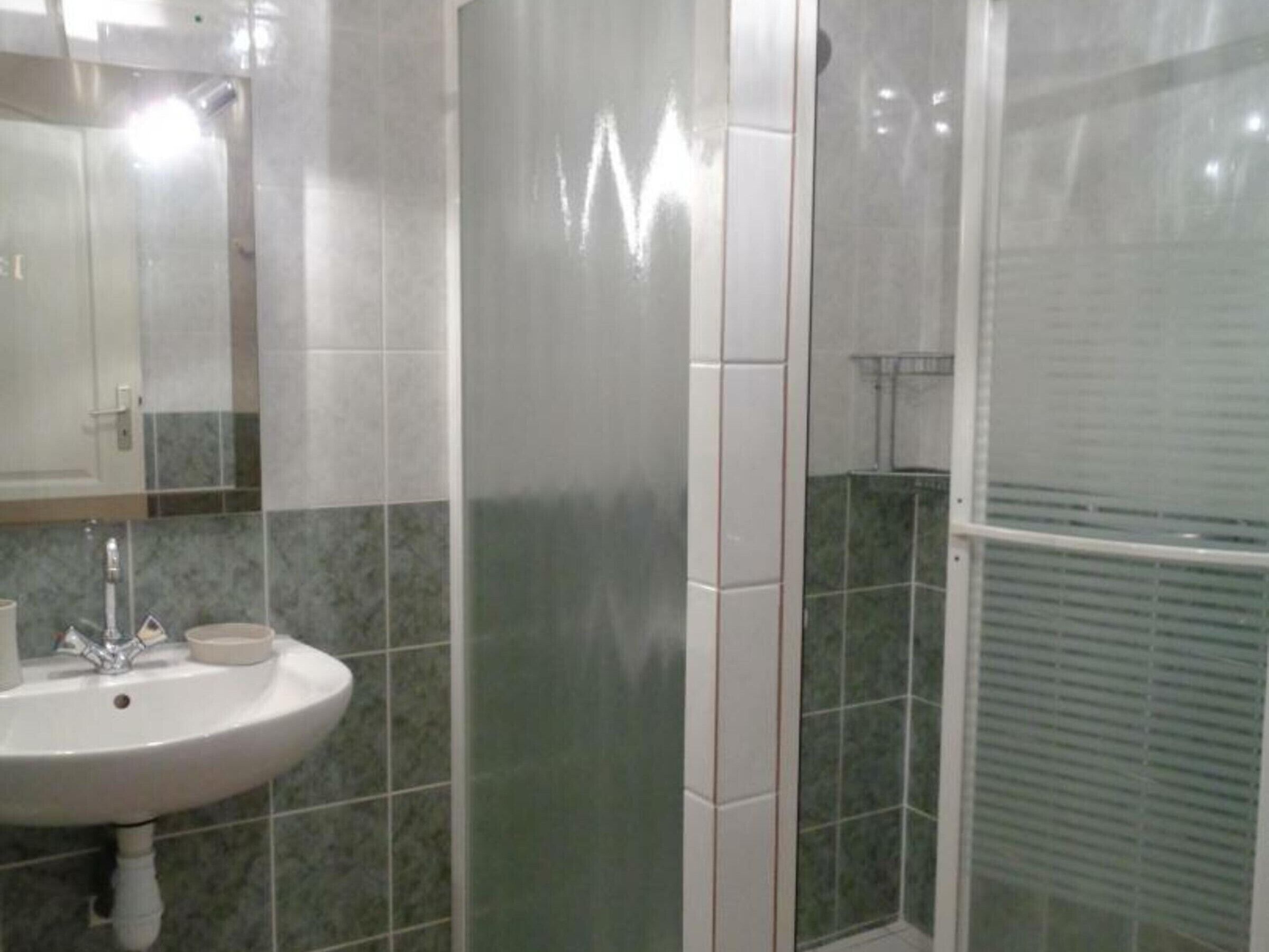 Une salle de bain avec un lavabo, un miroir et des murs carrelés.