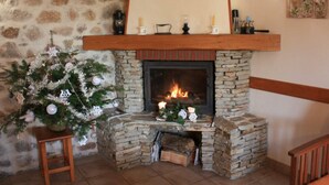 A stone fireplace with a mantel shelf, a Christmas tree, and a small table. - Cozy rental with garden, fireplace, and pet-friendly near Roanne (La Tuilière)