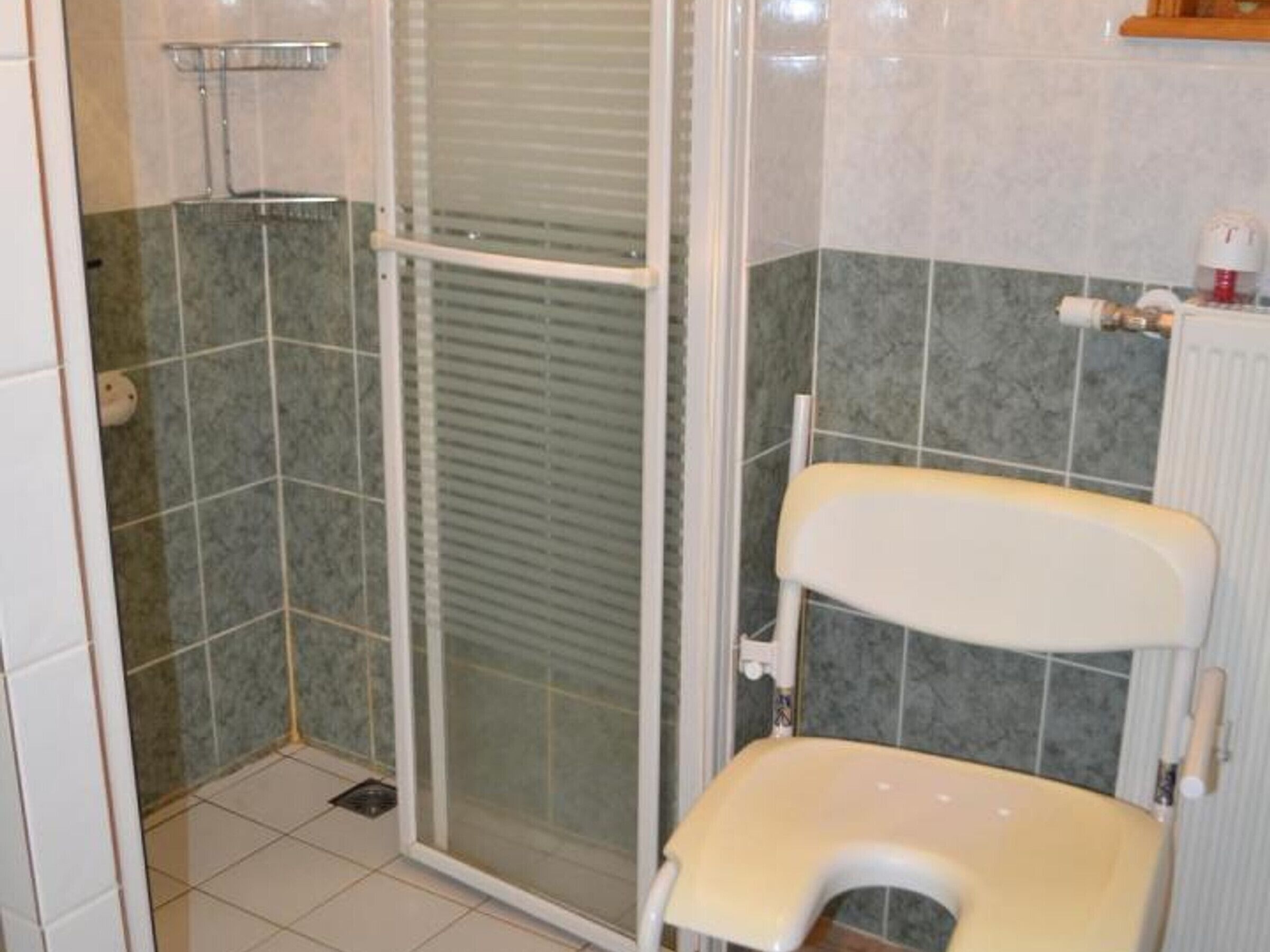 A bathroom with a shower, toilet, and a tiled floor.