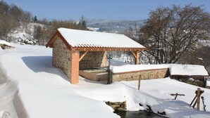 A stone building with a tiled roof, surrounded by snow-covered ground and trees. - Cozy rental with garden, fireplace, and pet-friendly near Roanne (La Tuilière)