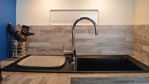 A kitchen with a black sink, stainless steel faucet, and a backsplash with a honeycomb pattern.