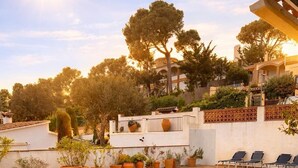 Une piscine dont le fond est recouvert de carrelage, entourée de plantes en pot et dotée d’un espace salon extérieur.