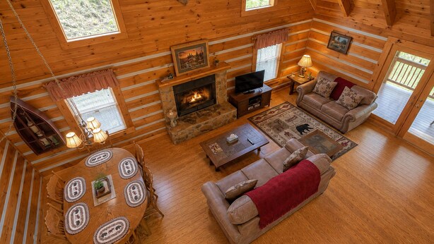 A cozy cabin interior with a fireplace, a sofa, a dining table, and a television.