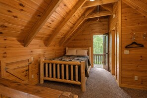 A cozy wooden cabin bedroom with a bed, a bench, and a door leading to a balcony. - Cozy Cabin, Pet Friendly, Close to Town, Great Mountain Getaway for Relaxation (Morganton)