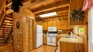A wooden cabin kitchen with a refrigerator, stove, microwave, and wooden cabinets.