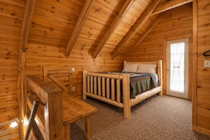 Une chambre dans un chalet en bois, avec un lit, un bureau et une fenêtre.