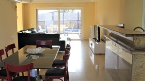 Un espace de vie compact comprenant un coin repas, une kitchenette et une porte-fenêtre coulissante donnant sur un patio.