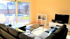 Un salon avec un canapé, une table basse, un téléviseur et une bibliothèque.