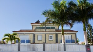 Un bâtiment à deux étages, doté d’un toit recouvert de tuiles, de grandes fenêtres et d’une clôture blanche en bois.