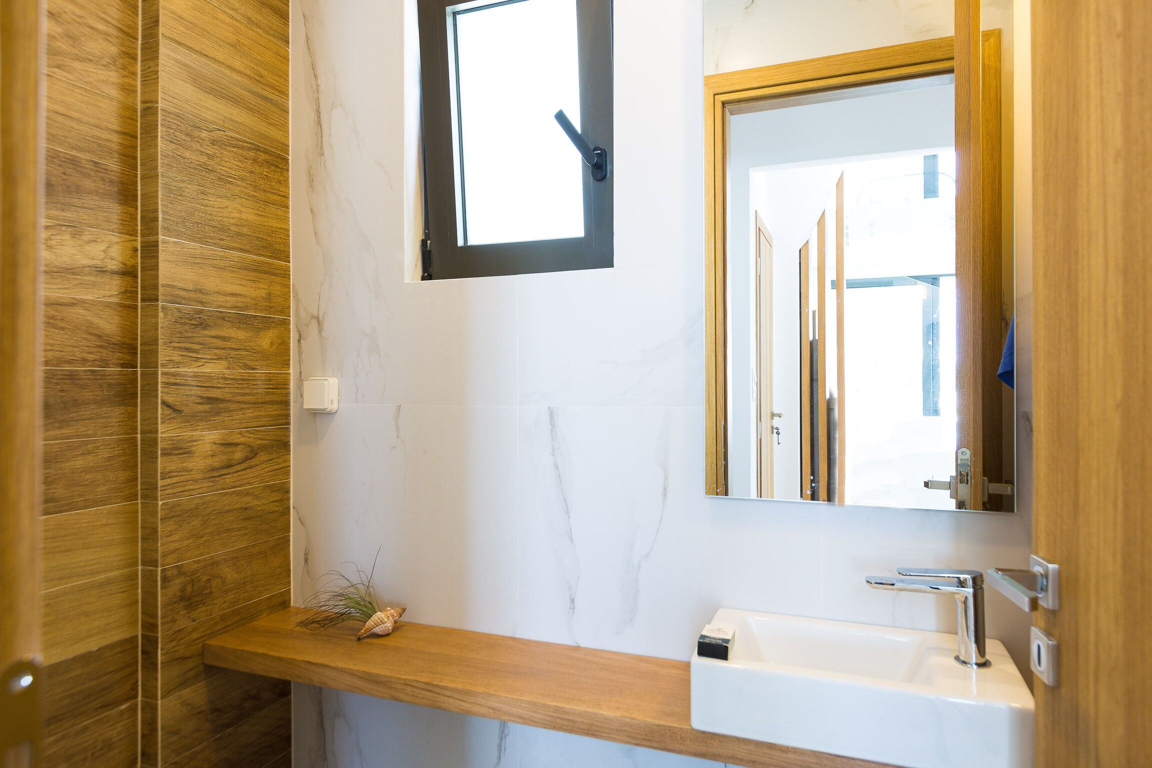 Une salle de bain avec un meuble-lavabo en bois, un lavabo blanc et un miroir.