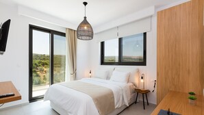 Un dormitorio moderno con una cama grande, un escritorio y vistas al exterior.