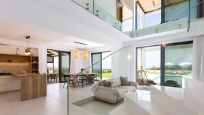 Un interior moderno con cocina, comedor y sala de estar con sofá y vista a una piscina.