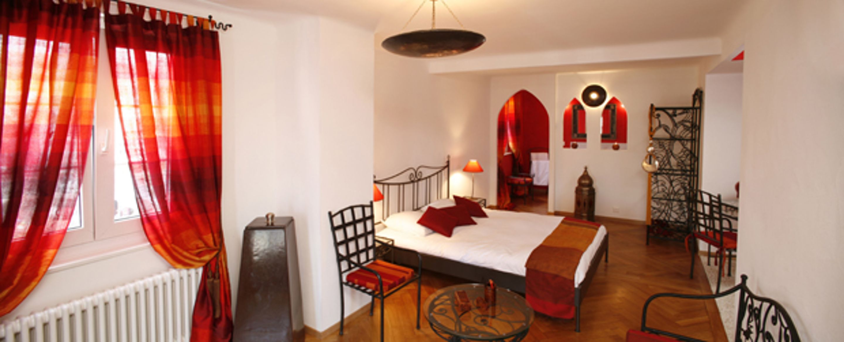Un dormitorio con cama, una silla, una mesa y un radiador.