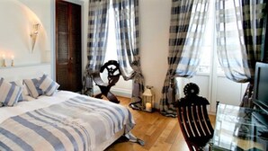 Un dormitorio con una cama, una silla, un televisor y una ventana con cortinas.