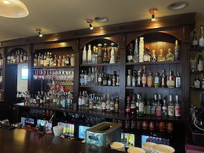 A bar with shelves stocked with various liquor bottles and glasses. - Hostellerie de Genève (Vevey)
