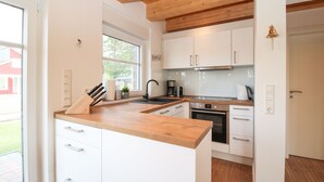 Une cuisine moderne avec des armoires blanches, un plan de travail en bois et une hotte de cuisine en acier inoxydable.