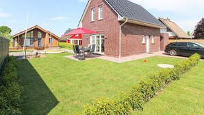Une maison d’habitation avec une façade en briques rouges, un toit en pente et une pelouse bien entretenue.