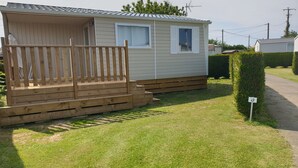 Una casa móvil con terraza de madera y un pequeño porche.