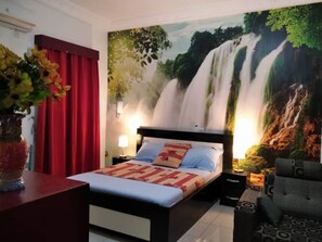 A hotel room with a bed, red curtains, a wall mural of a waterfall, and a nightstand with a lamp. - PLEASANT STUDIO (Cocody)
