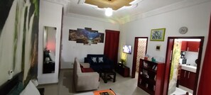 A living room with a sofa, a coffee table, a TV, and a bookshelf. - PLEASANT STUDIO (Cocody)